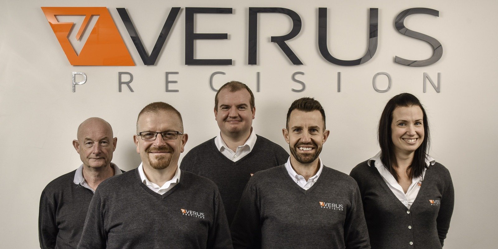 Corporate team group photo in front of company signage